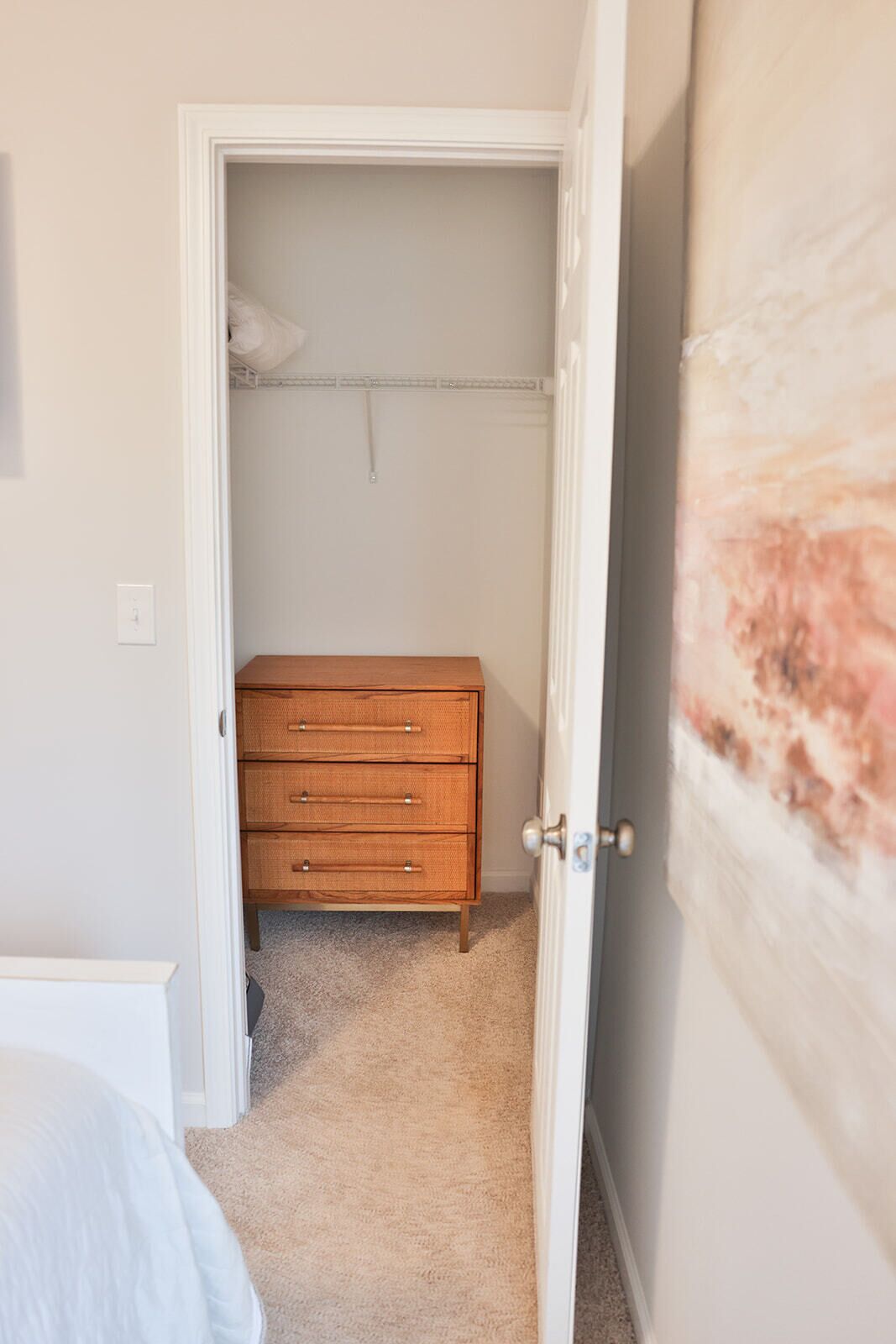 Ein Schlafzimmer mit einem hölzernen Schminktisch, einem Kleiderschrank mit Kleiderstange und einem Teppichboden.