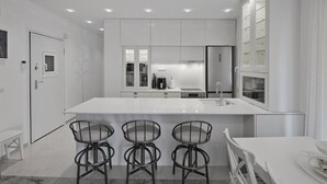 A modern kitchen with a large island, bar stools, and built-in appliances. - Belva Blue Glyfada Modern 2BR Walk to Ctr & Beach (Glifada)