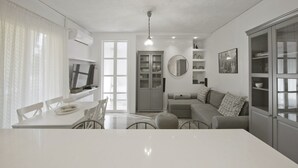 A modern kitchen with a dining table, chairs, a built-in oven, and a large window. - Belva Blue Glyfada Modern 2BR Walk to Ctr & Beach (Glifada)