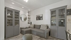 A modern living room with a grey sectional sofa, a round mirror, and built-in glass-fronted cabinets. - Belva Blue Glyfada Modern 2BR Walk to Ctr & Beach (Glifada)