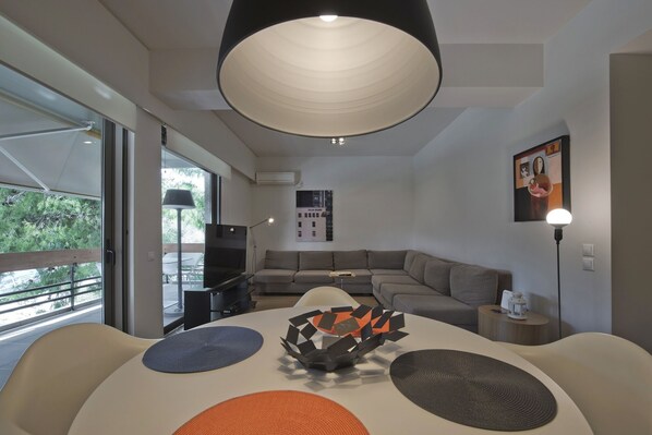 Un salon moderne avec une grande table ronde, des canapés et un téléviseur.