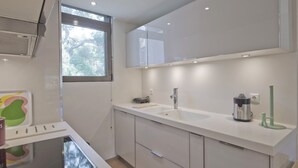 A modern kitchen with white cabinetry, a stainless steel sink, and a coffee maker. - Sea Breeze Spacious Apt near Vouliagmeni Beach (Vouliagmeni)