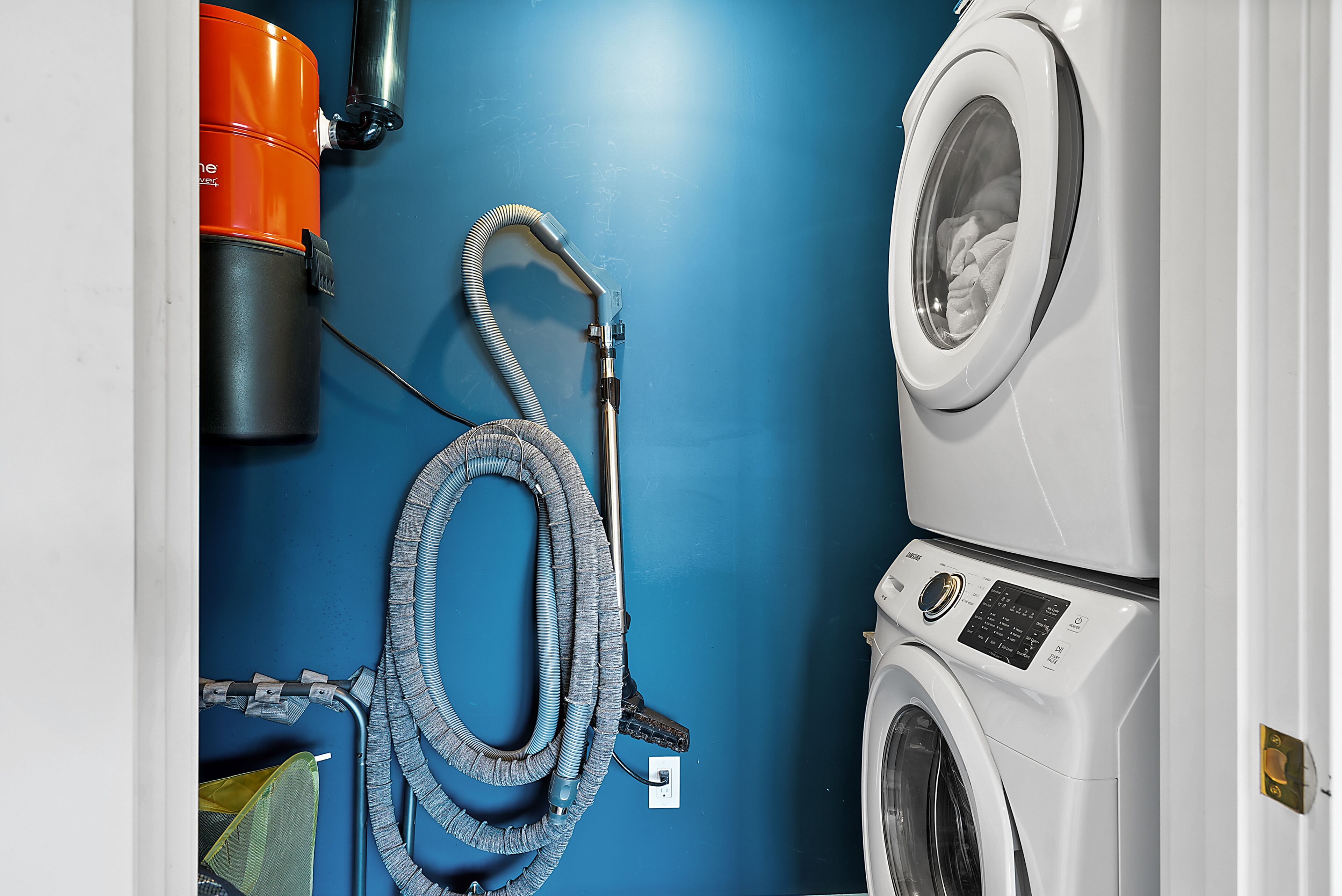 A laundry area with a washing machine and a hose.