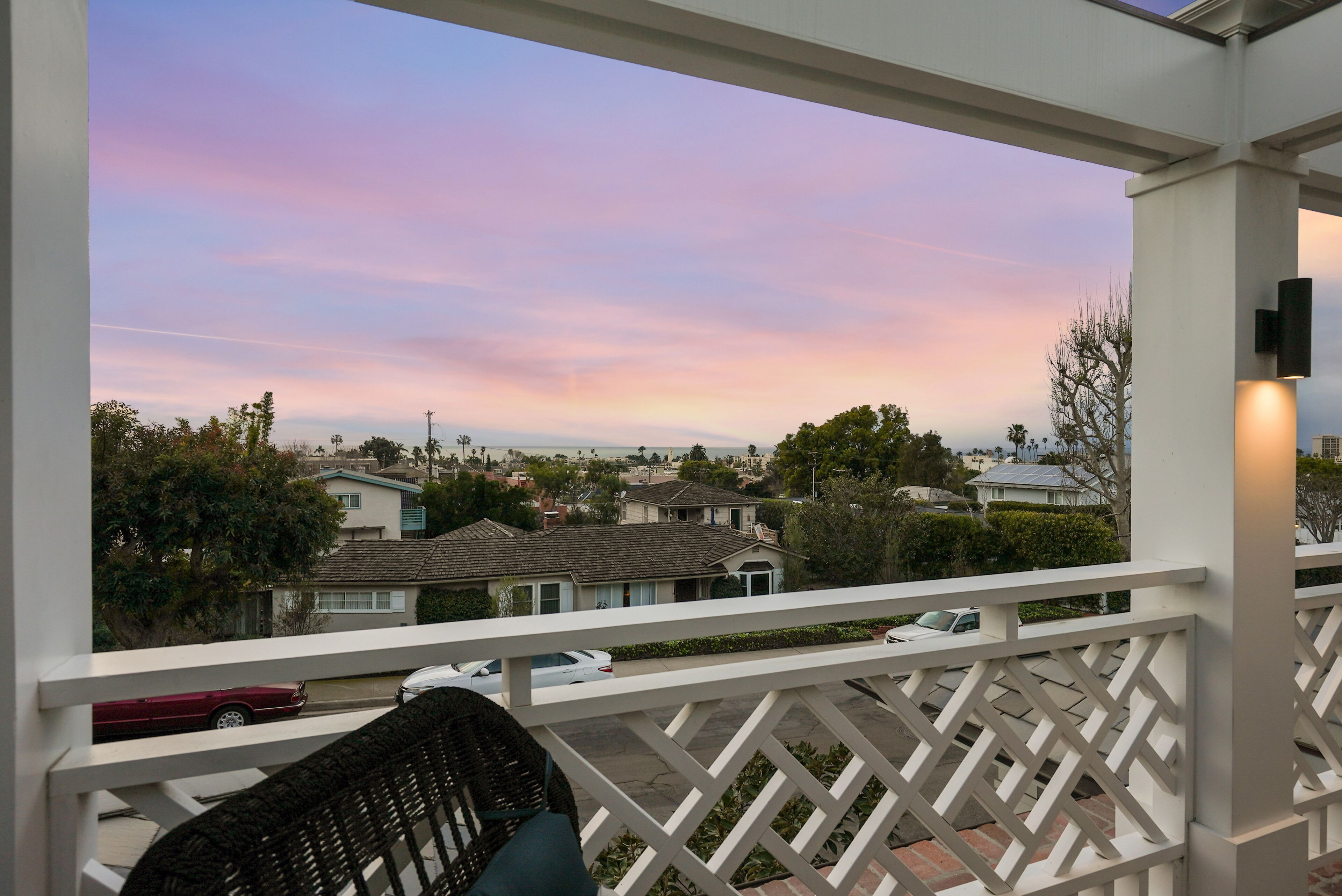 A balcony with a view of residential houses and a sunset sky.