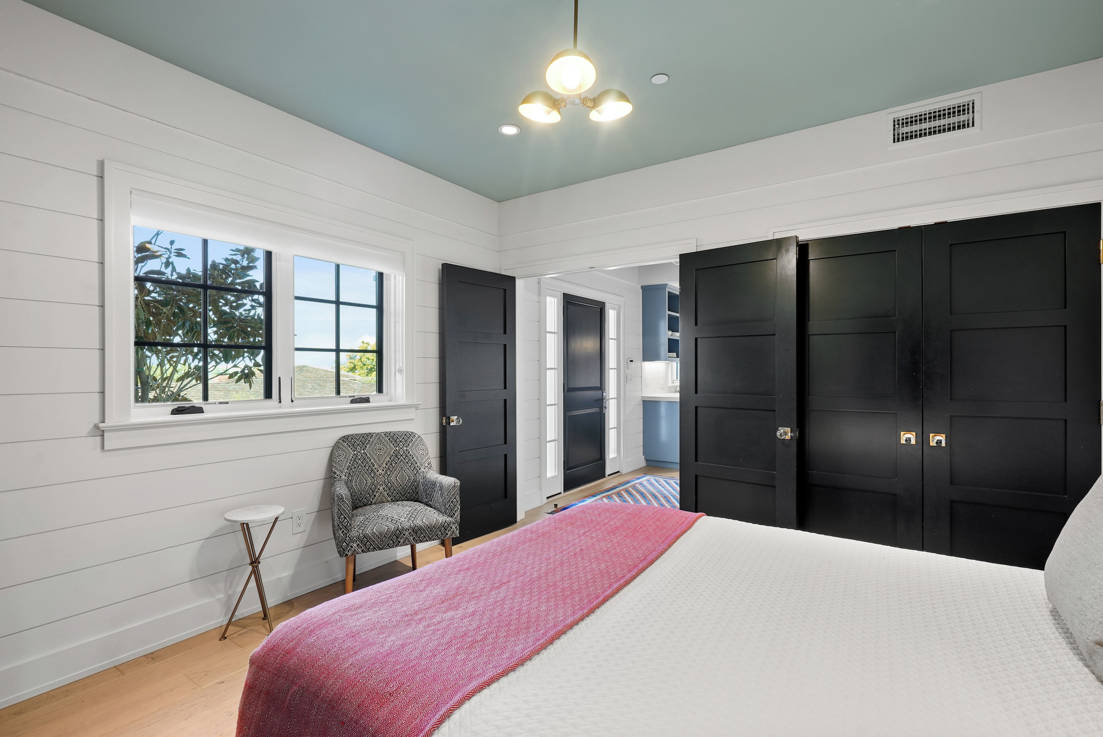 A bedroom with a bed, a chair, a window, and a door.