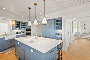 Una cocina moderna con armarios azules, encimeras blancas e iluminación colgante.