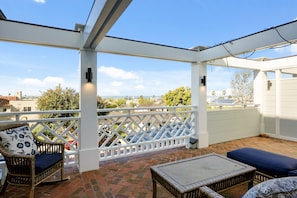 Un patio cubierto con mobiliario de mimbre y una cerca blanca de celosía.
