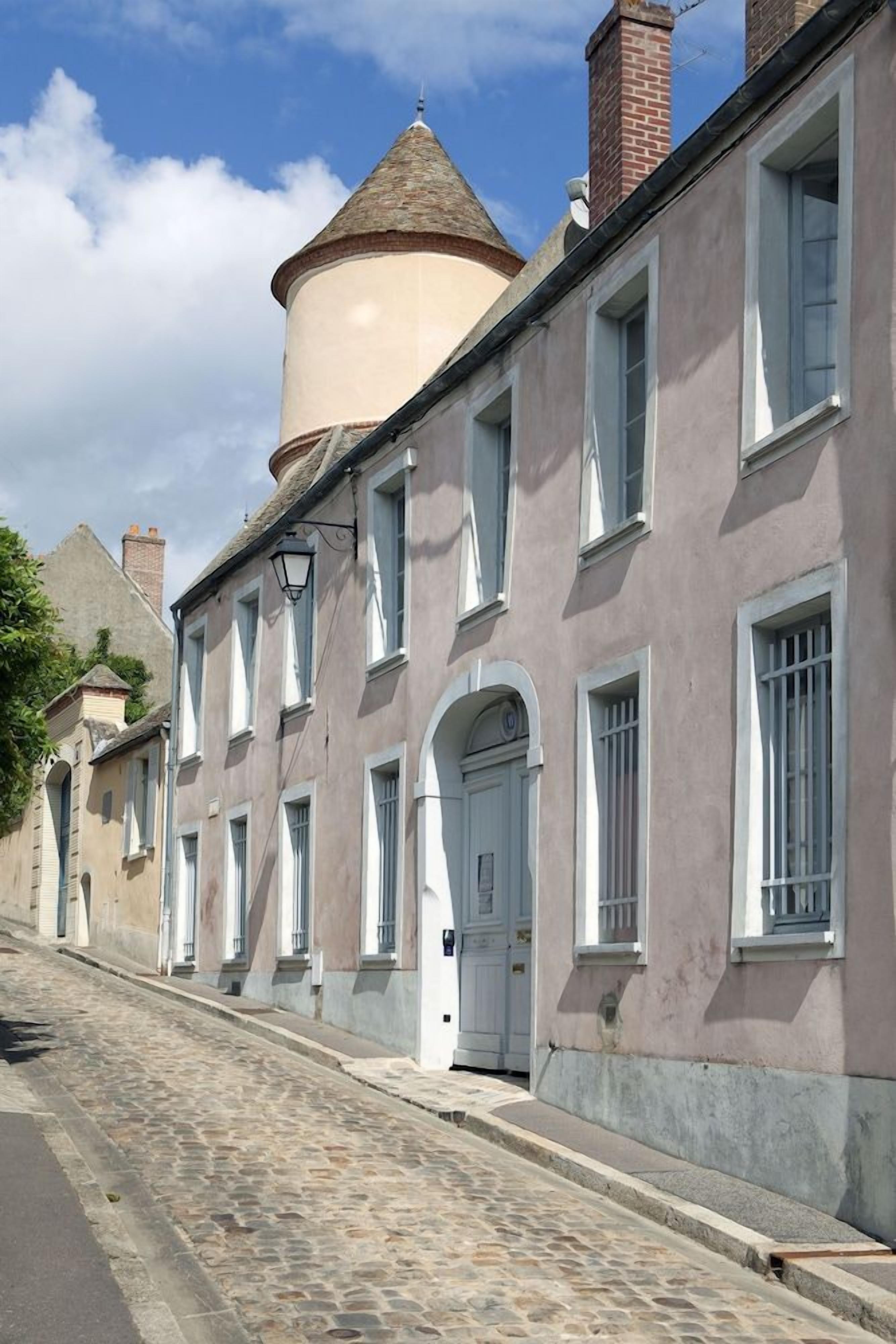 A historic street with buildings featuring arched windows and a prominent tower.