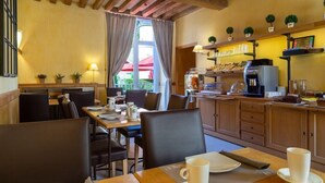 Un coin repas accueillant avec des tables et des chaises en bois, un comptoir de cuisine équipé d’appareils électroménagers et une fenêtre agrémentée de rideaux.