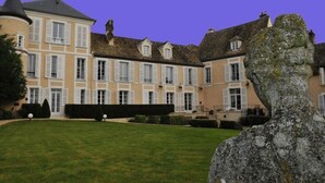 Un grand immeuble à étages, doté d’une façade symétrique et d’une entrée centrale avec un escalier.