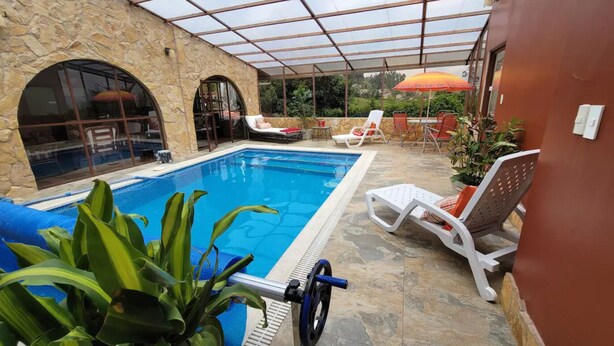 Piscina com espreguiçadeiras e área de estar coberta.