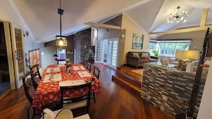 Uma sala de jantar ampla com toalha de mesa vermelha, cadeiras de madeira e um candelabro.
