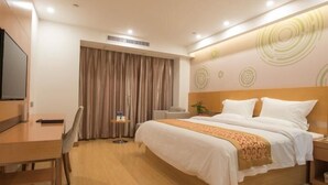 A hotel room with a bed, a desk, a chair, a TV, and a curtain.