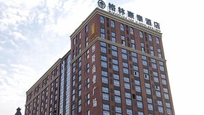 A tall brick building with multiple windows and a sign at the top.