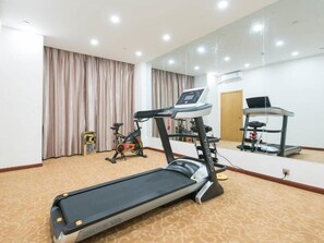 Un gimnasio con cinta de correr, bicicleta estática y equipo de ejercicio.