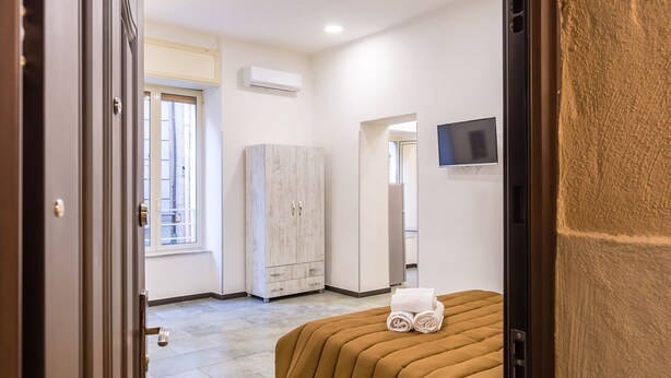 A hotel room with a bed, a wardrobe, a television, and a window.