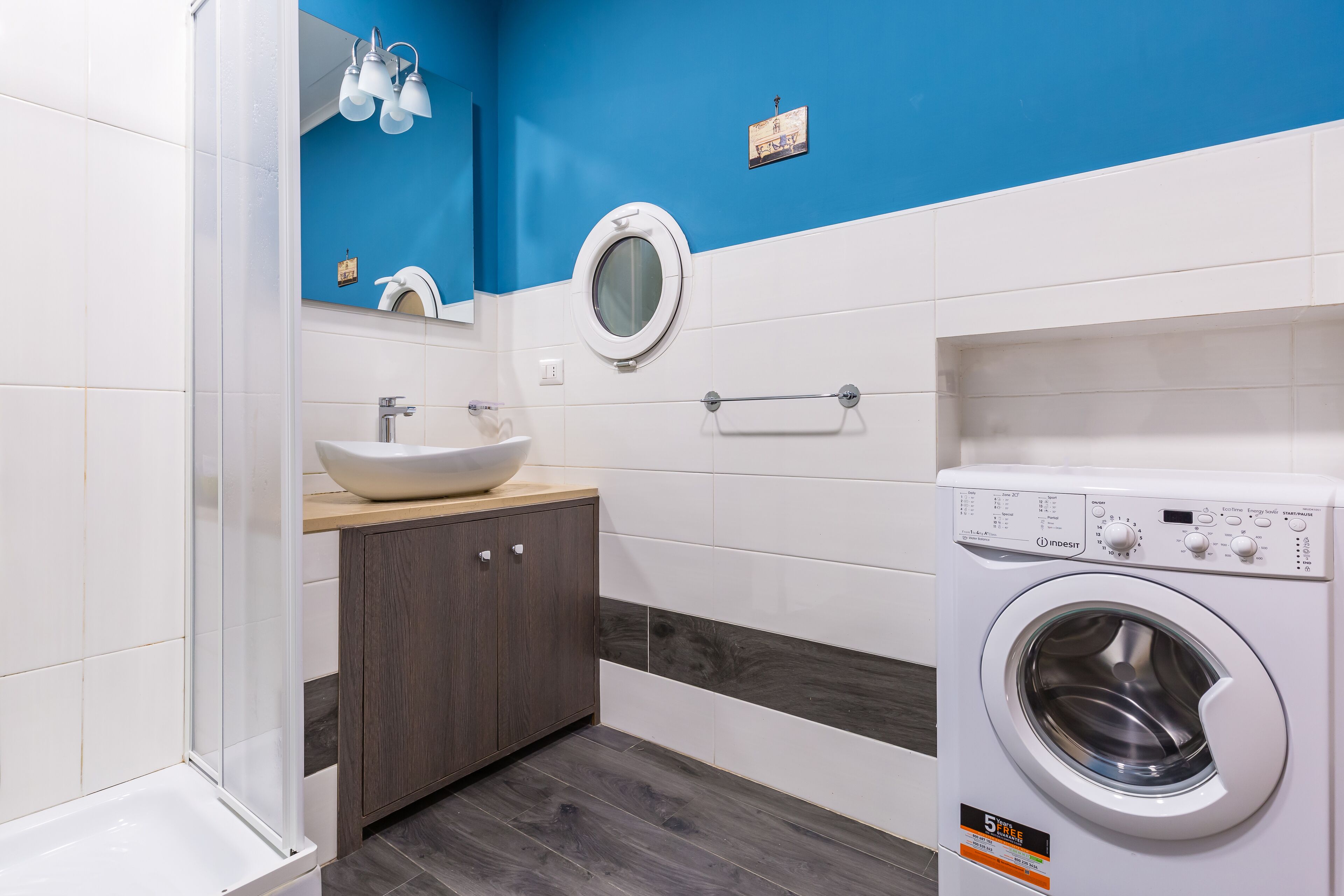 A modern bathroom with a sink, mirror, and a washing machine.