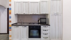 A compact kitchen with white cabinetry, a gas stove, a microwave, and a built-in oven. - Gelso Complex - Apartment 2 (Napoli)