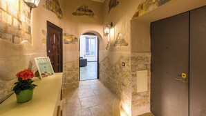 A hallway with stone walls, a wooden door, and a sign indicating a visit. - Gelso Complex - Apartment 2 (Napoli)