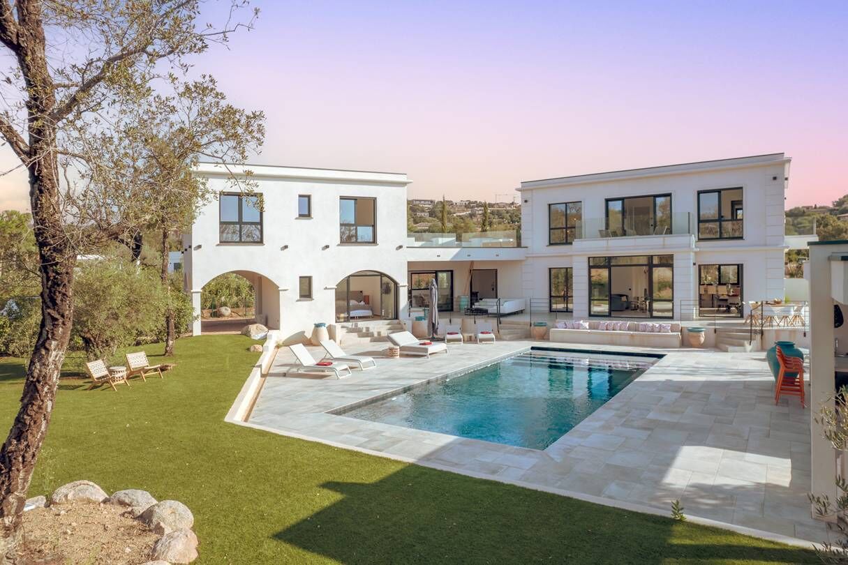 Une maison moderne à deux étages, dotée d’une piscine, d’un espace salon extérieur et d’une pelouse bien entretenue.