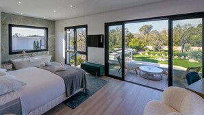 A modern bedroom with a large bed, a bathtub, and a view of a landscaped garden through large sliding doors. - Villa Blue Pearl, 10 pers, piscine chauffée, 10 minutes plage à pieds (SAINTE LUCIE DE PORTO VECCHIO)