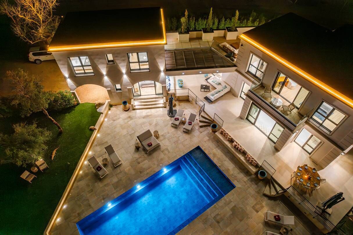 A modern house with a swimming pool, outdoor seating, and a well-lit patio area.