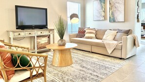 A living room with a television, sofa, coffee table, and decorative plants. - Contemporary 4-Bed Home Steps from Downtown & ATT Center (San Antonio)
