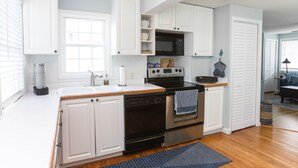 A modern kitchen with white cabinets, a microwave, an oven, and a dishwasher. - Classic Beach Cottage with front porch view of water (Carolina Beach)