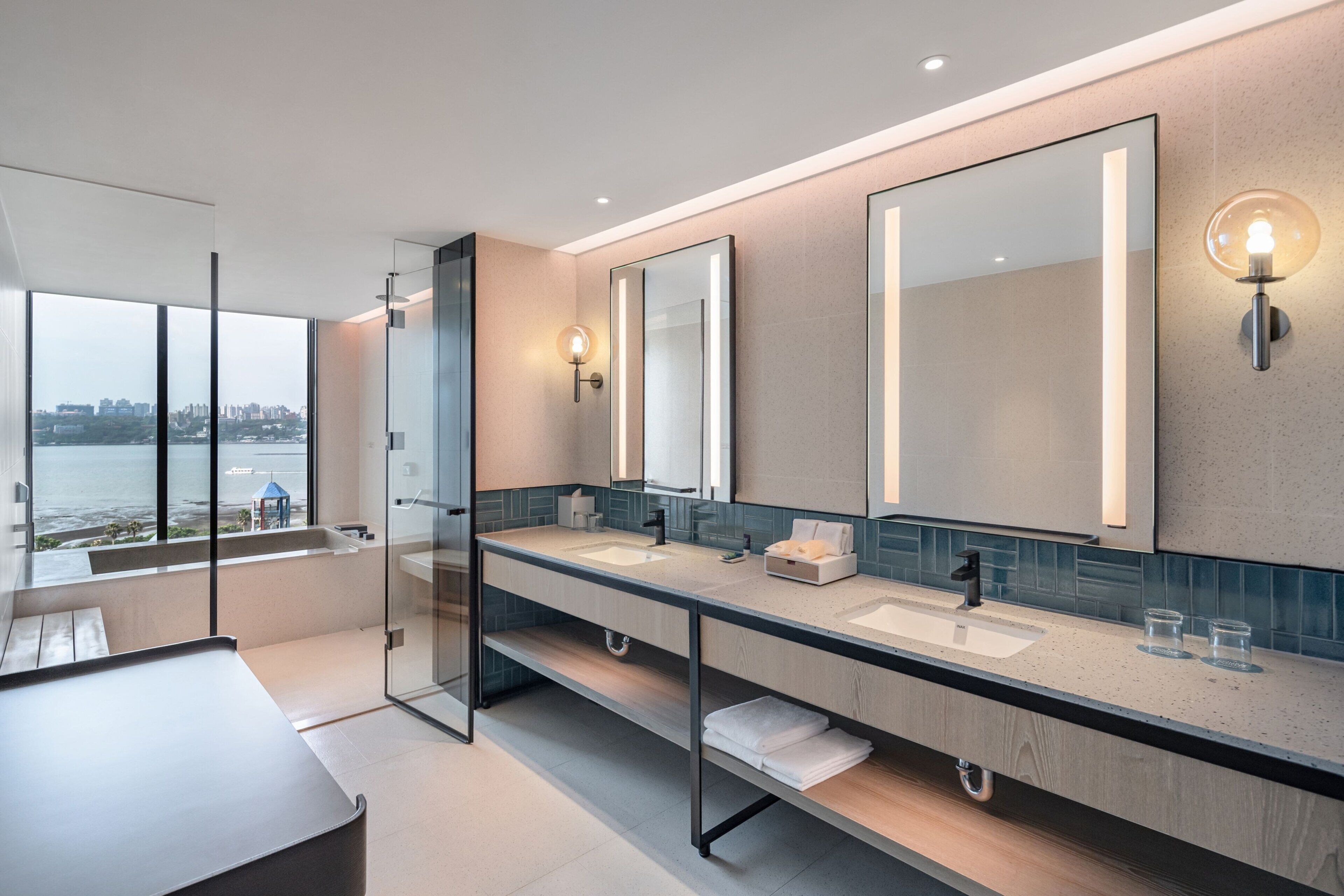 A modern bathroom with dual sinks, large mirrors, and a glass shower enclosure.