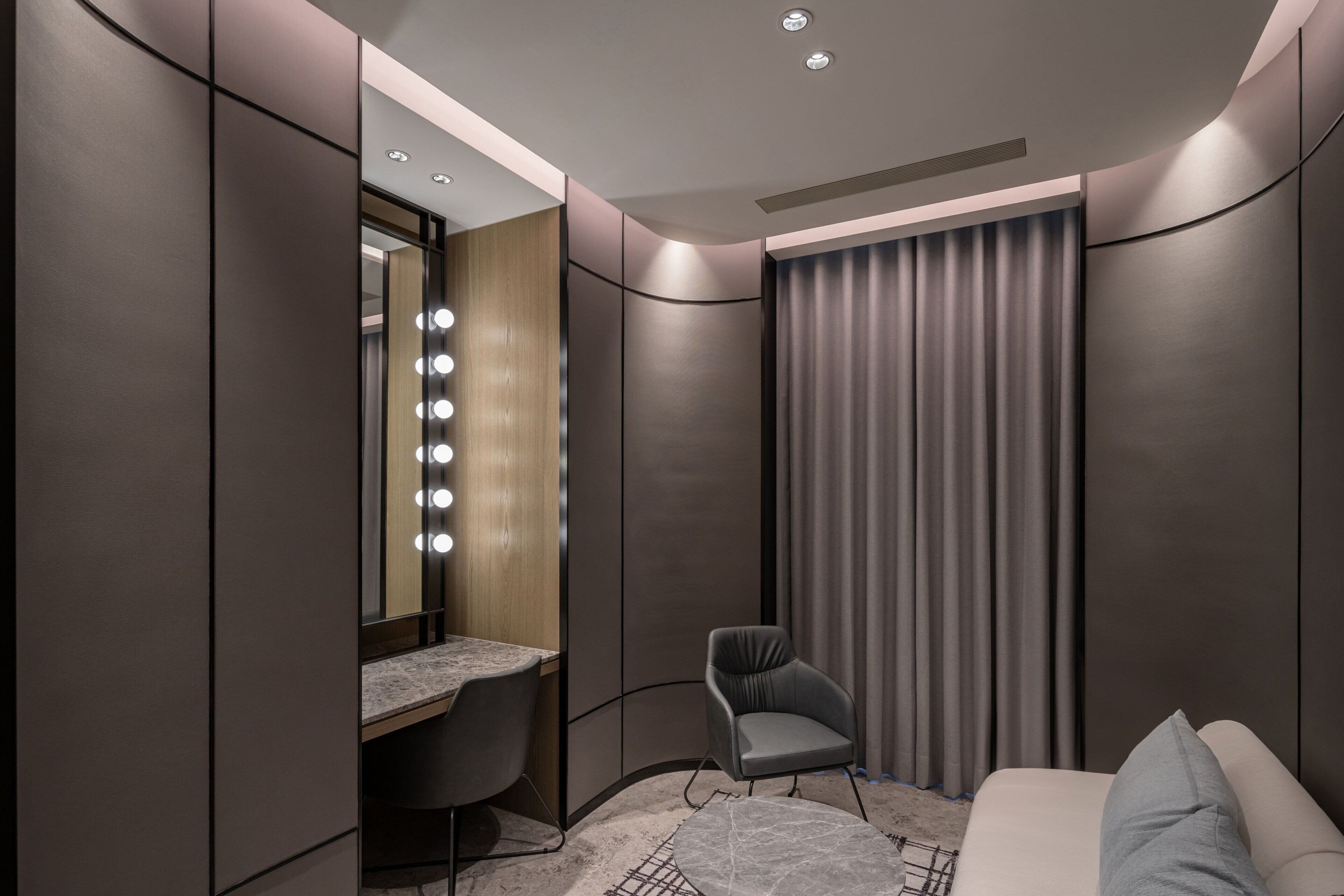 A modern bedroom with a vanity, a chair, and a bed.
