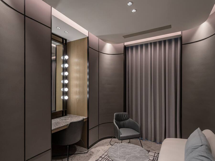 A modern bedroom with a vanity, a chair, and a bed.