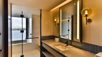 A modern bathroom with a large mirror, a sink, and a glass shower enclosure.