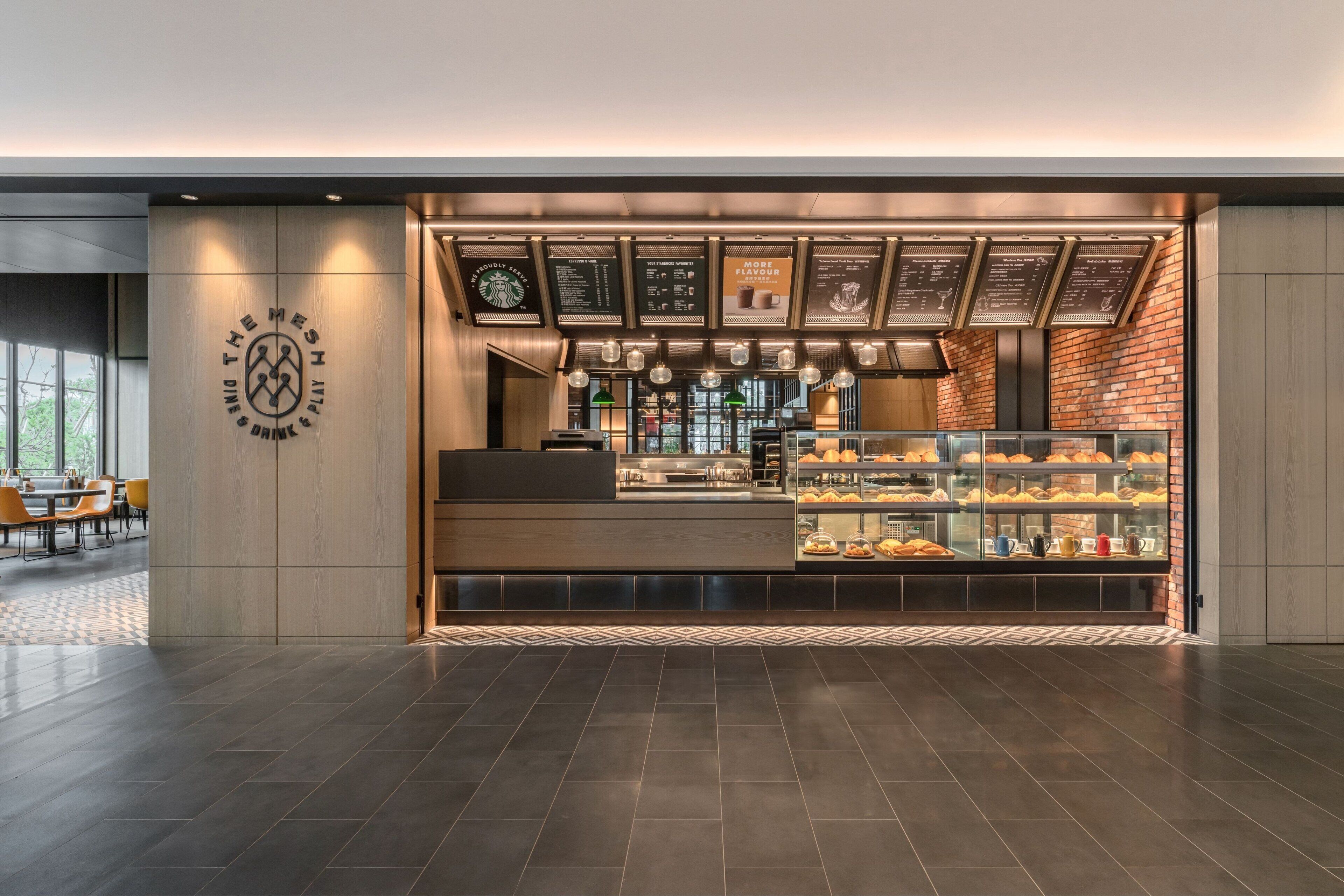 A modern coffee shop with a counter displaying pastries and a menu board above.