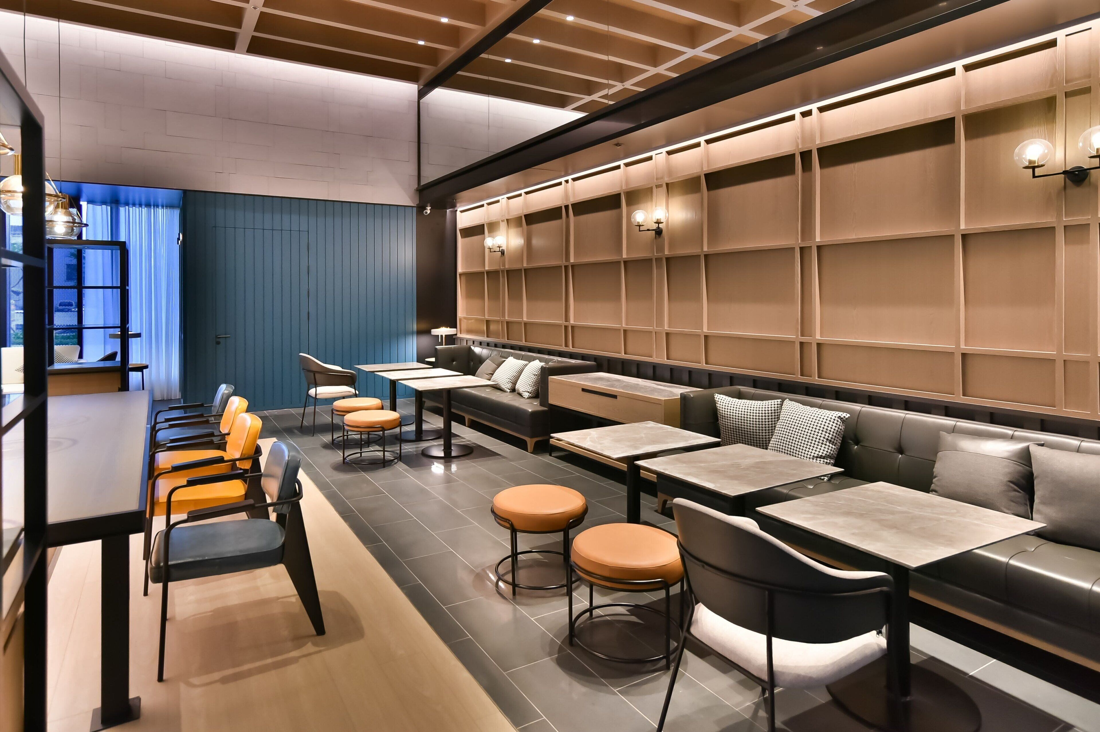 A modern restaurant with a long communal table, individual seating, and a blue accent wall.