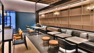 A modern restaurant with a long communal table, individual seating, and a blue accent wall.