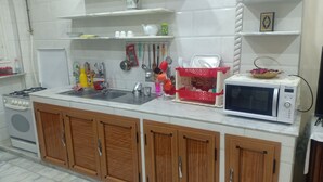 A kitchen with a sink, stove, wooden cabinets, and a microwave. - Dream Home (Setif)