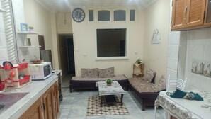 A compact living space with a kitchenette, a sofa, a dining table, and a patterned rug. - Dream Home (Setif)