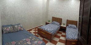 A bedroom with two wooden beds, a checkered floor, and a plain wall.