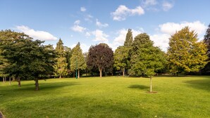 Un parc où l’on trouve une grande variété d’arbres et une pelouse bien entretenue.