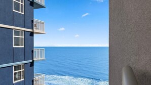Um edifício de vários andares com varandas voltadas para uma praia e oceano.