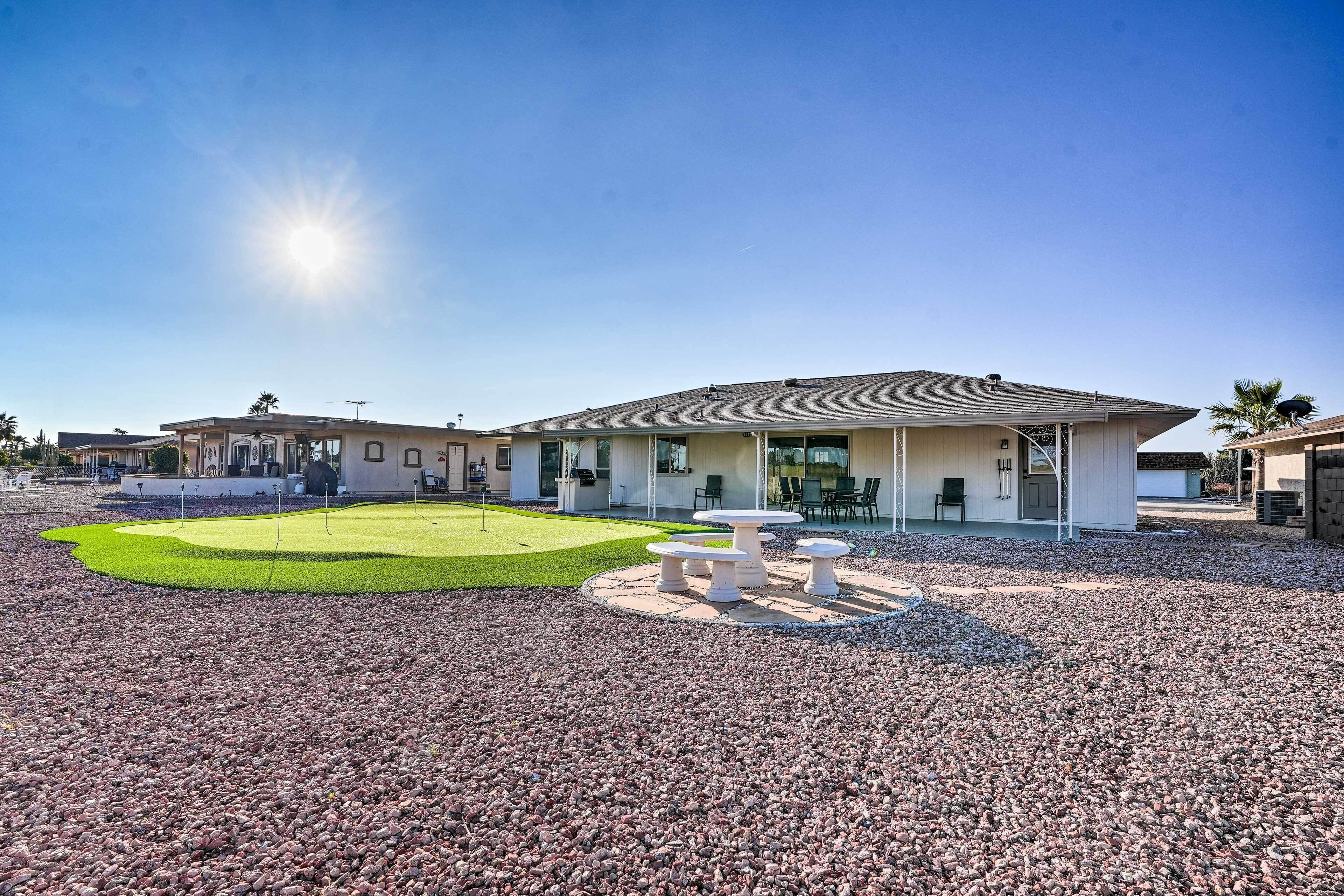 A modern building with a flat roof, large windows, and a gravel courtyard with outdoor seating.