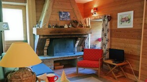 Ein gemütliches Wohnzimmer mit Kamin, Fernseher und einem roten Sessel.