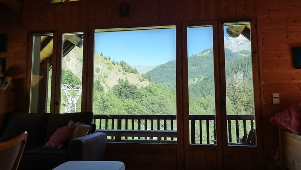 Eine Holzhütte mit großen Fenstern und Blick auf die Berge.