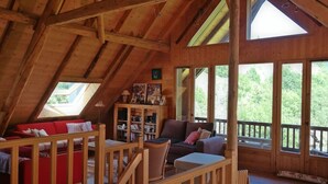 Ein gemütliches Holzambiente mit einem roten Sofa, einem braunen Sessel und einem Bücherregal.
