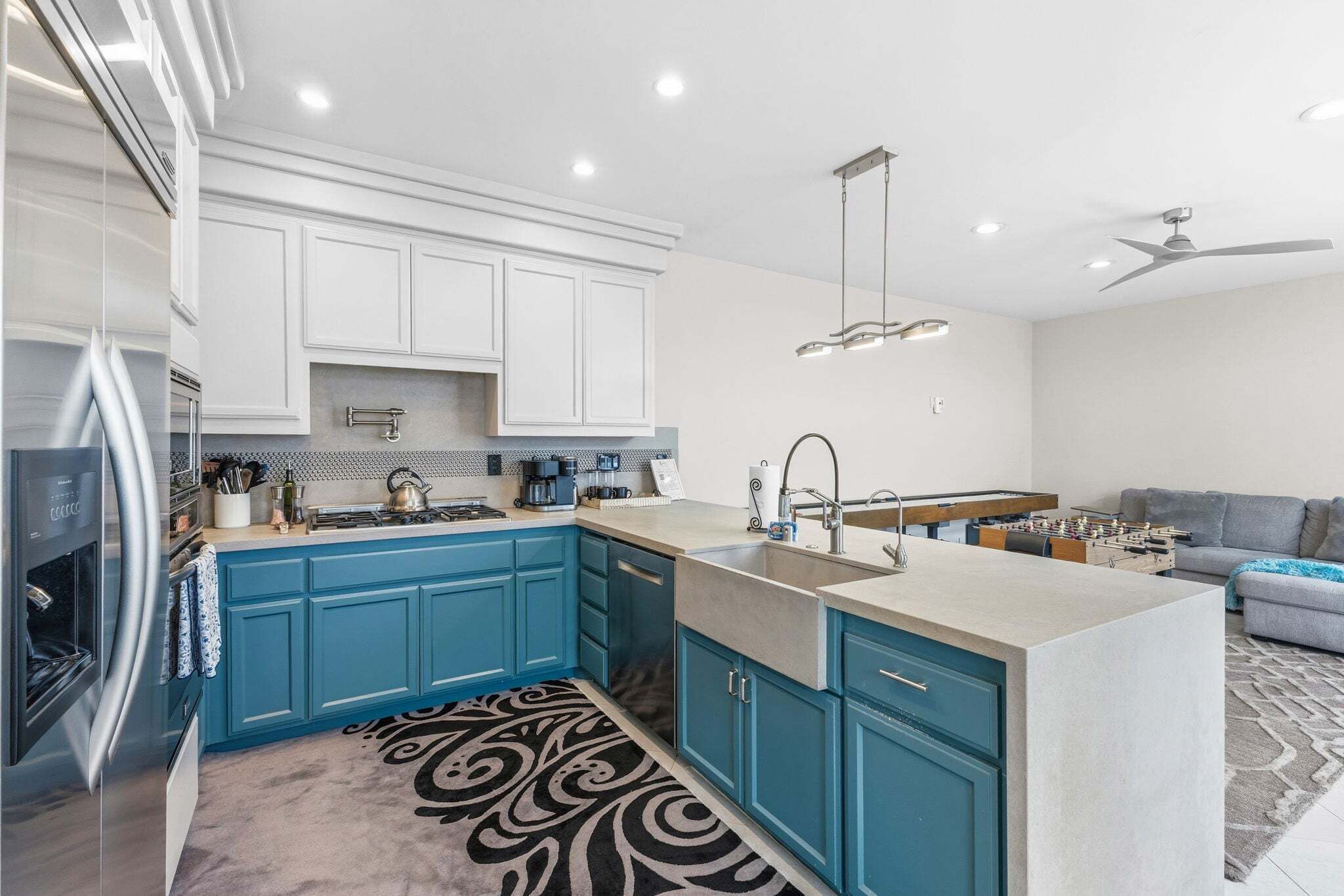 A modern kitchen with teal cabinets, a central island, and a built-in oven.