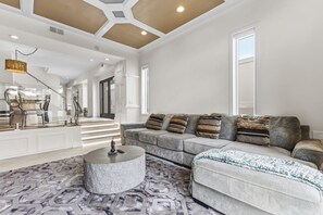 A spacious living room with a grey sofa, patterned rug, and a round coffee table.