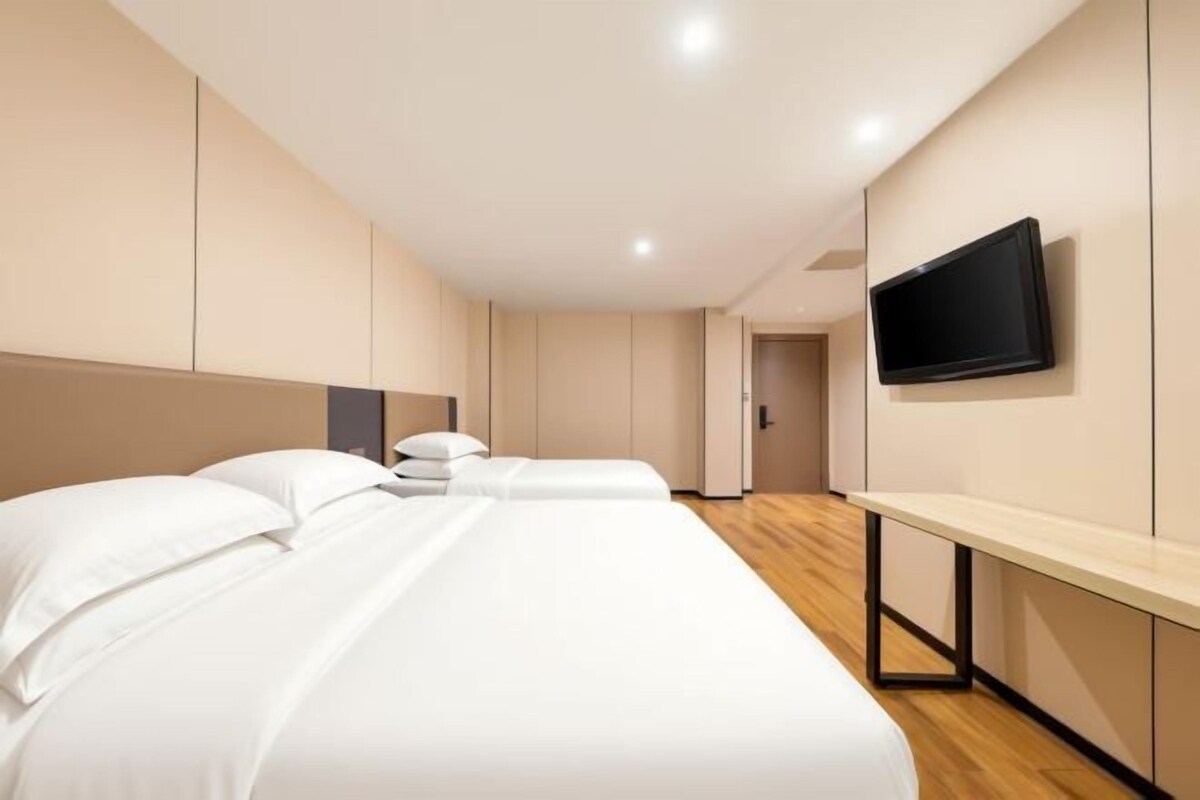 Habitación de hotel con una cama grande, una mesita de noche, un televisor de pantalla plana montado en la pared y piso de madera.