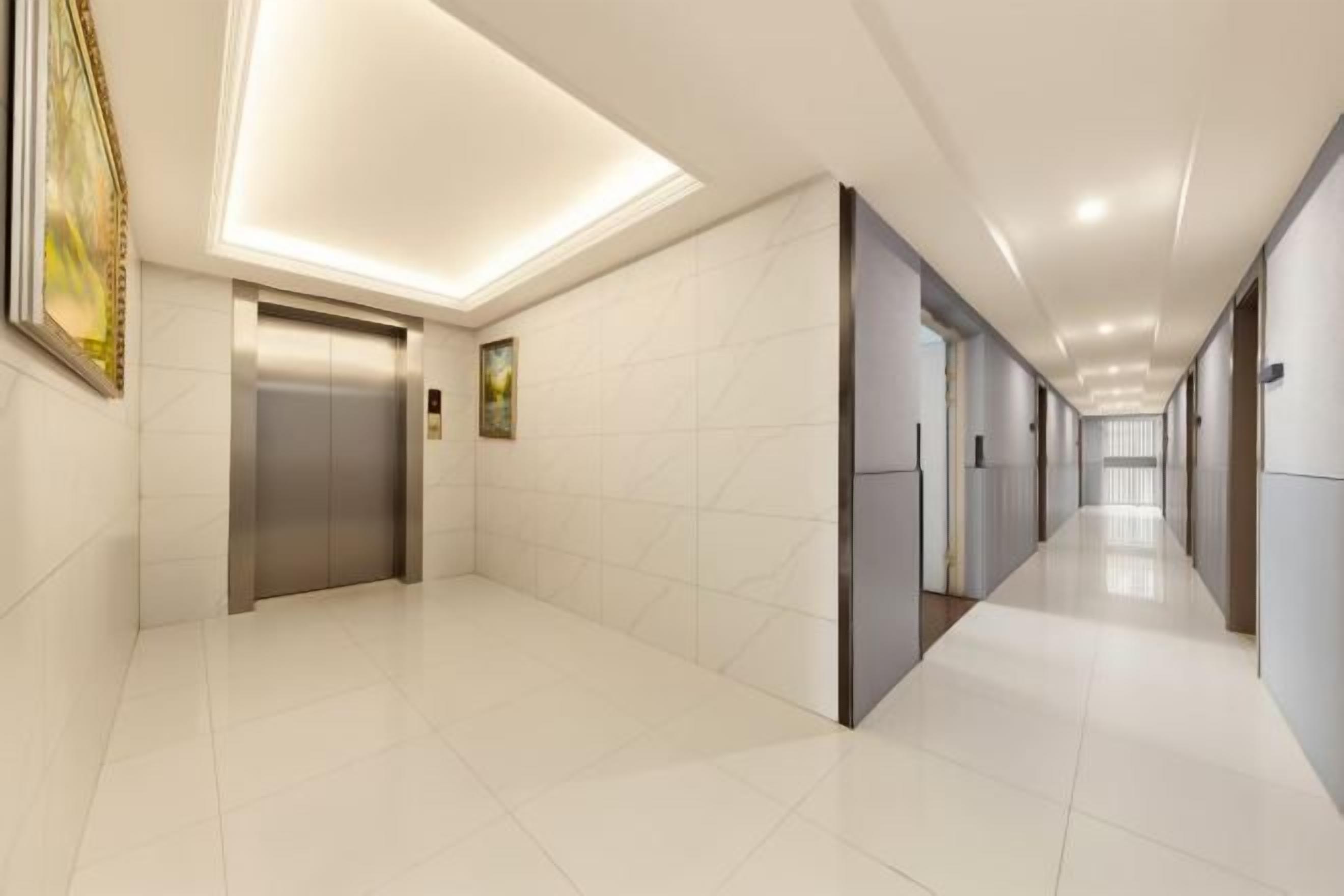 A long, narrow hallway with a modern elevator and doors on both sides.