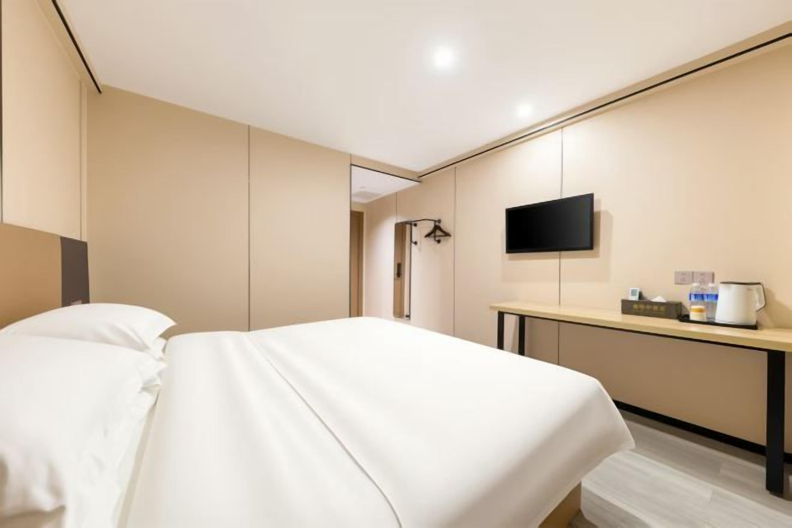 Une chambre d’hôtel comprenant un lit, un téléviseur fixé au mur, une table de chevet avec une machine à café et un miroir.