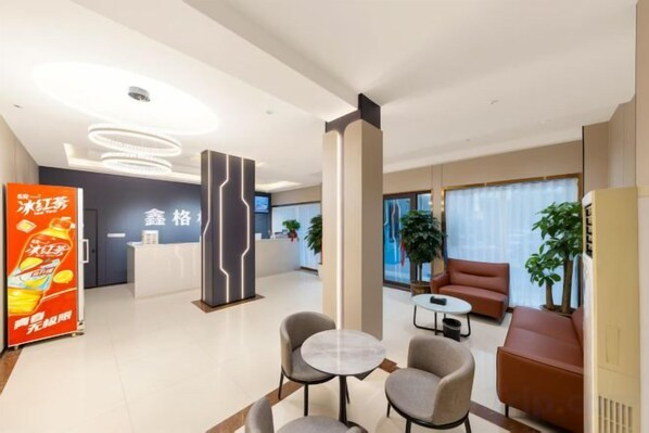 A modern hotel lobby with a reception desk, seating area, and a large plant. - Xingelin Business Hotel (Daye)